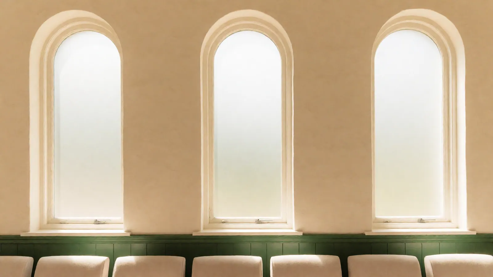 Tall plain windows along the side of the chapel, the glass clear and the walls bare